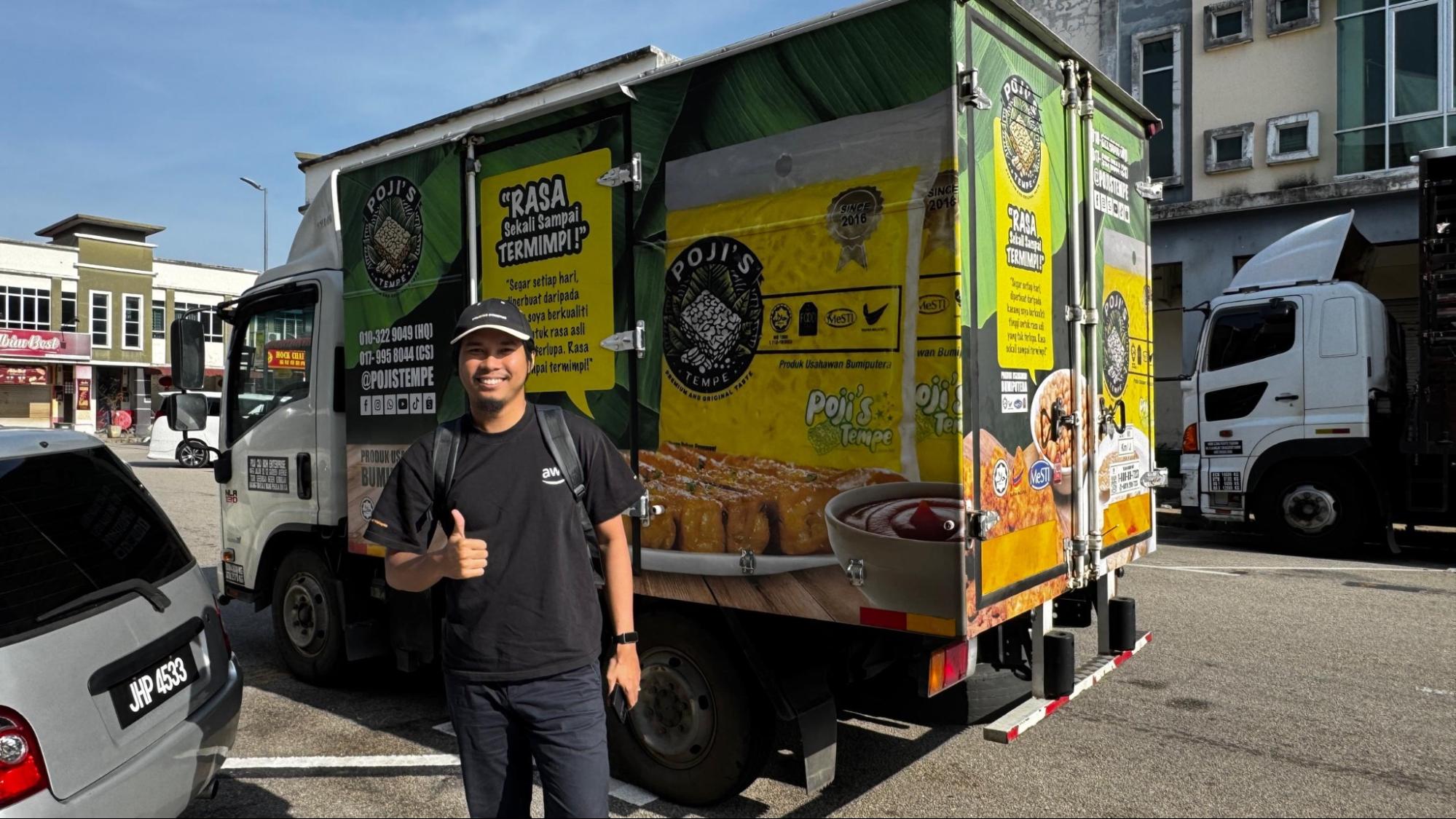 Man standing beside a branded Pojis Tempe delivery truck in a parking area.