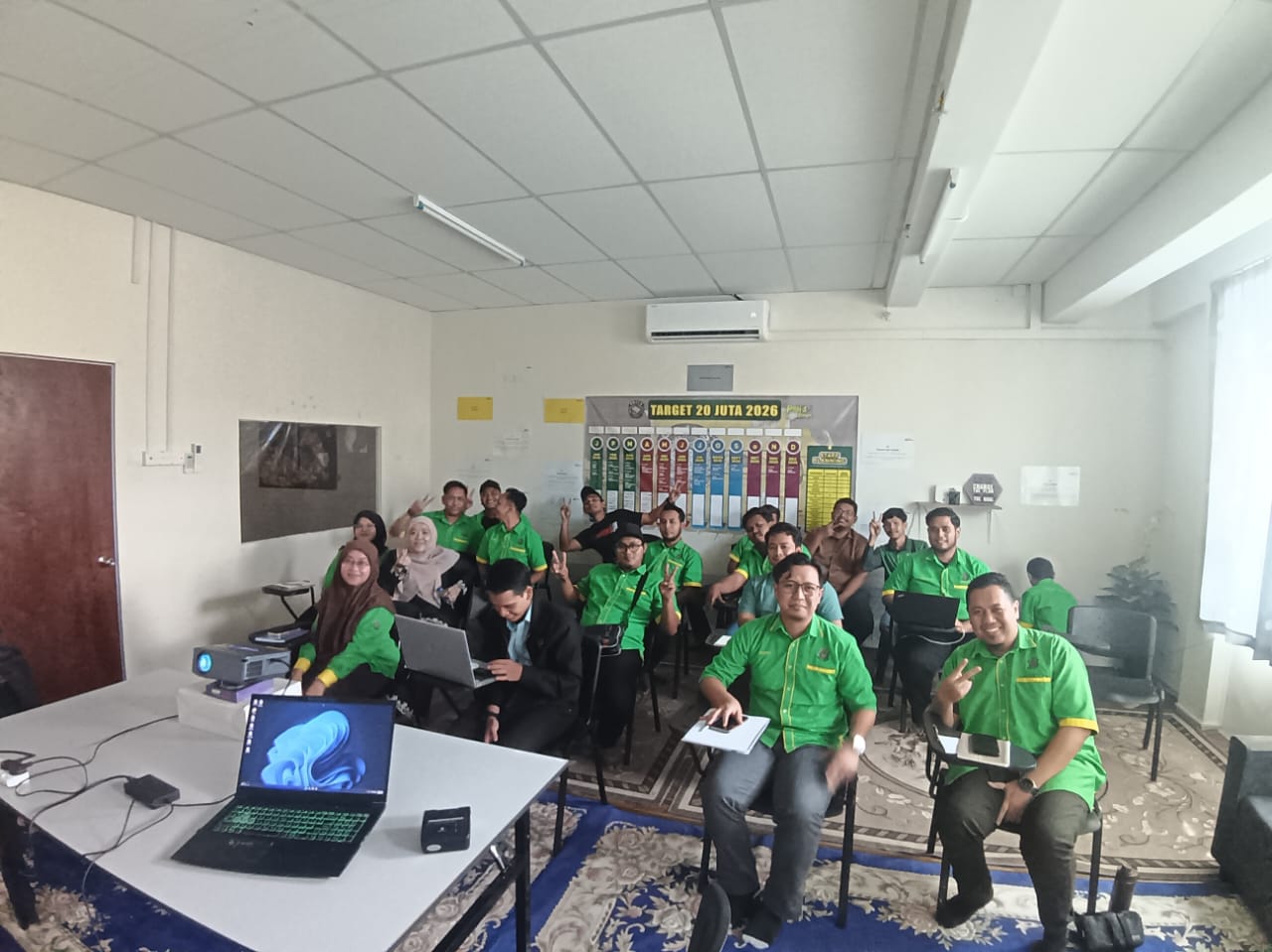Group photo of a team attending a training session in a meeting room with laptops and a projector.